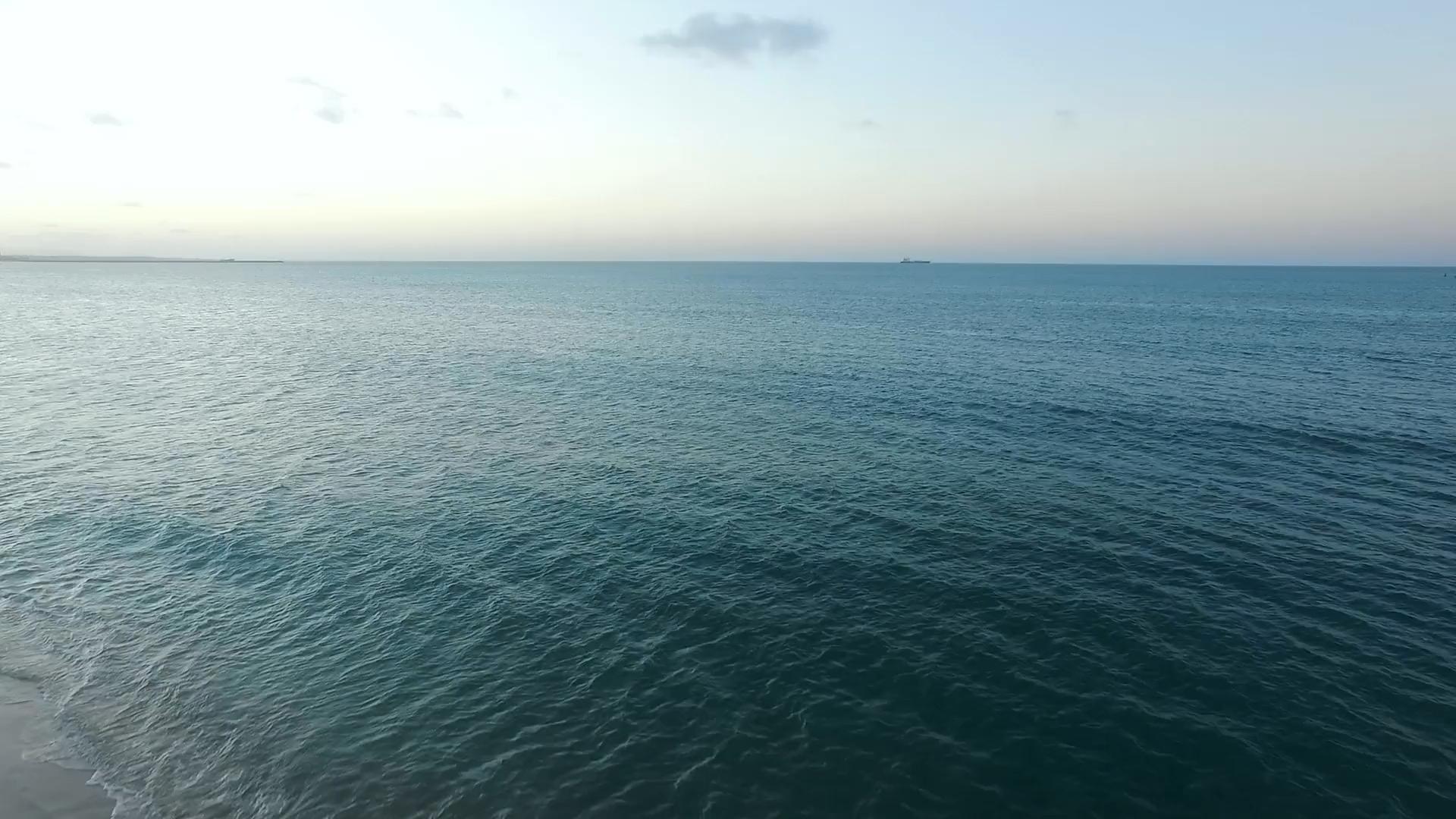 View of the ocean surface with a ship on the horizon