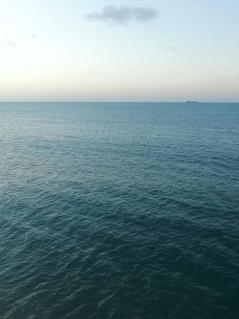 View of the ocean surface with a ship on the horizon
